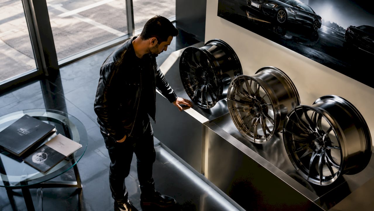 Man inspecting concave car wheels in garage
