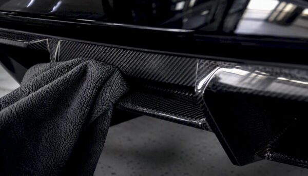 Close-up of microfiber towel cleaning carbon fiber spoiler