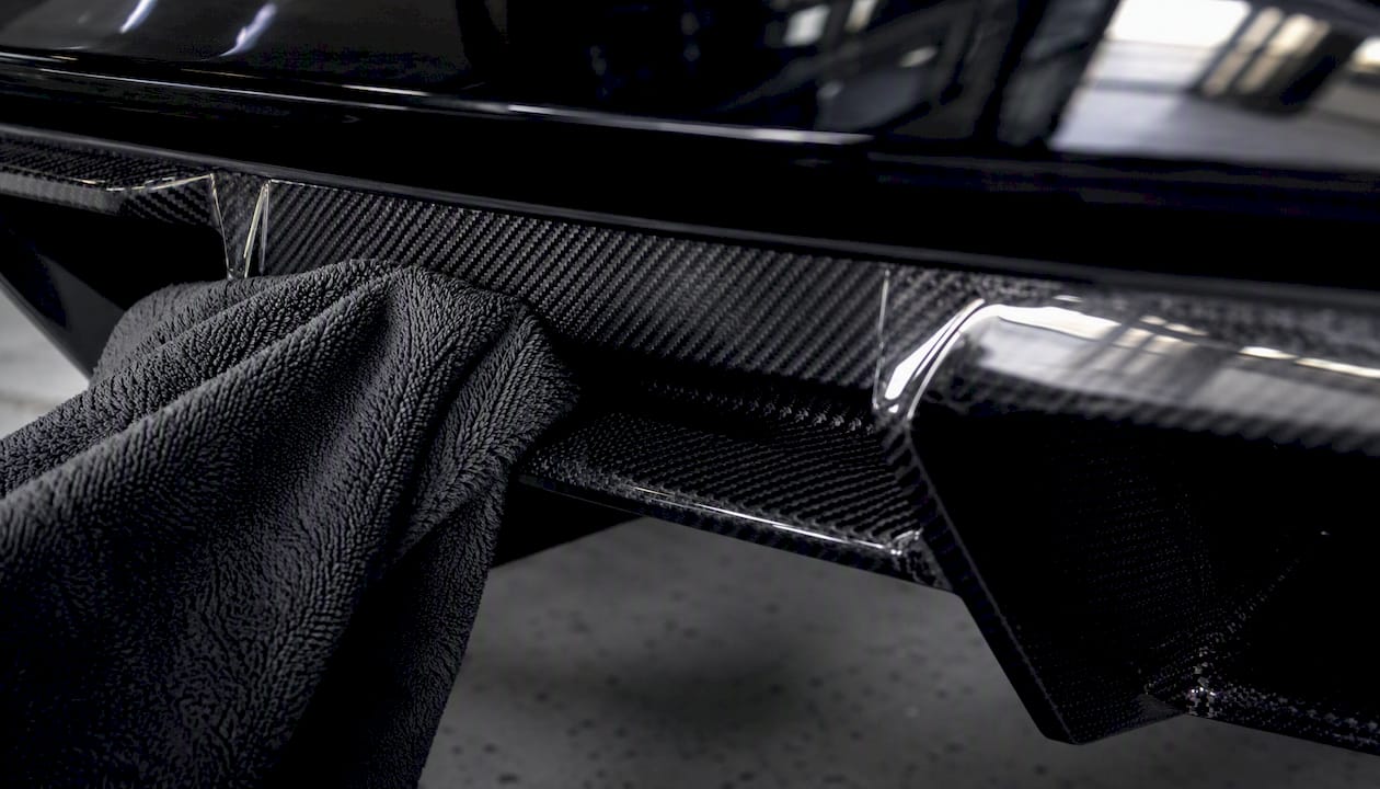 Close-up of microfiber towel cleaning carbon fiber spoiler